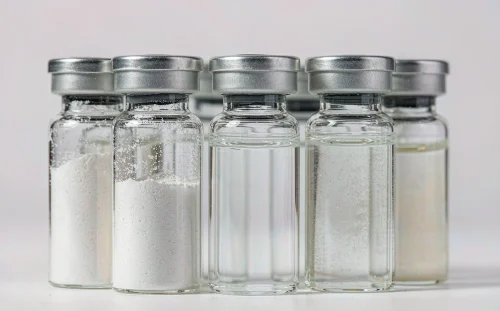 Small glass vials of white surfactant powder and clear liquid surfactant samples on a white background, one vial showing slight cloudiness, CMC and Krafft point comparison